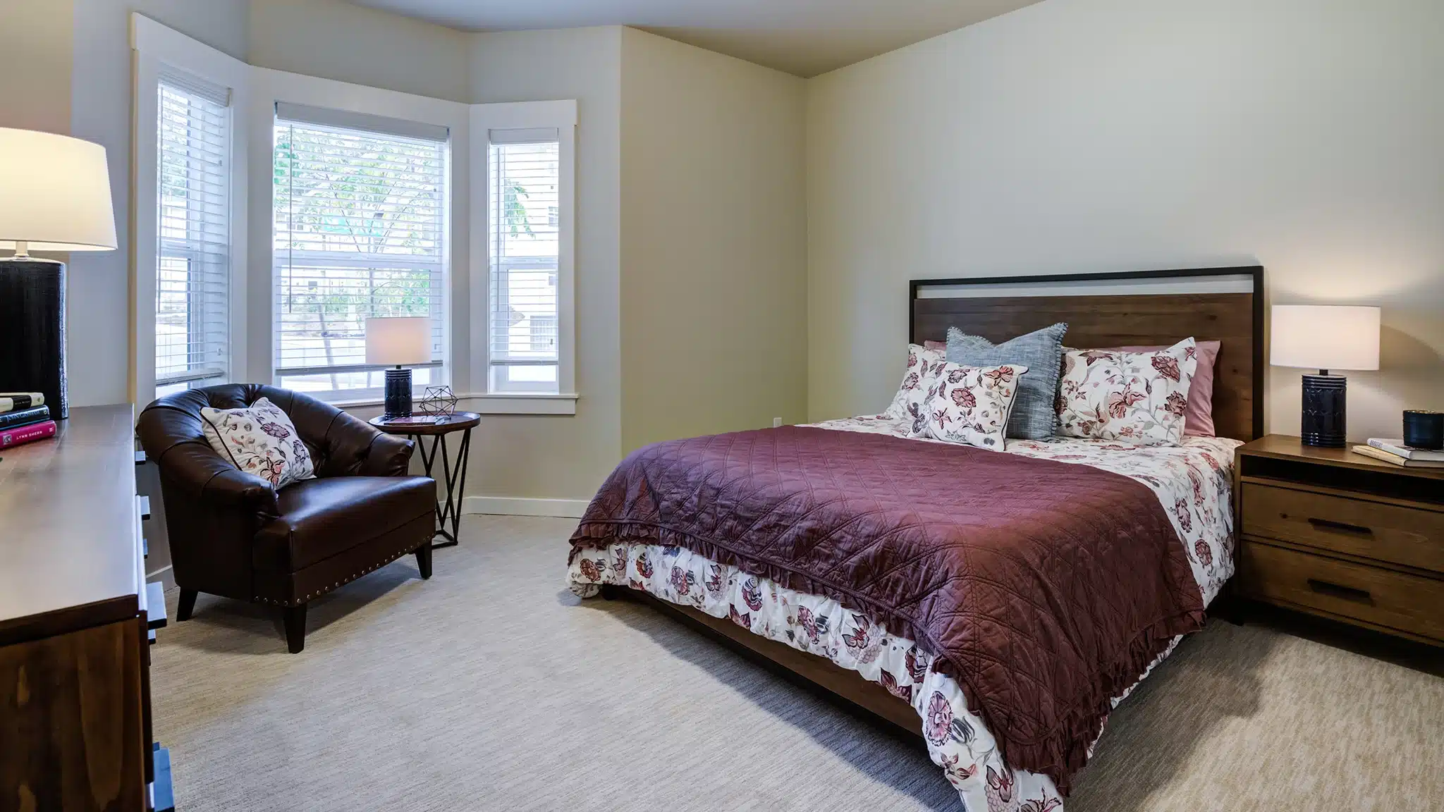 Private bedroom with bed, dresser, and window in a senior living apartment.