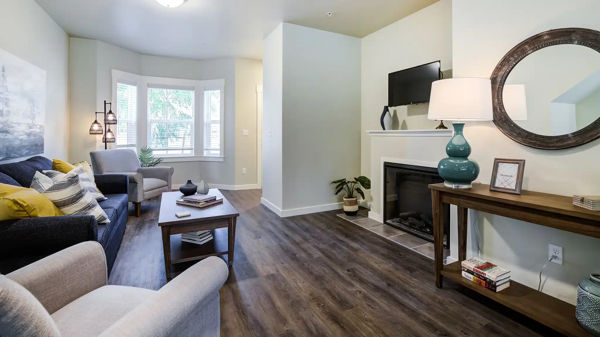 Living room with sofa, table, and large windows in a senior living apartment.