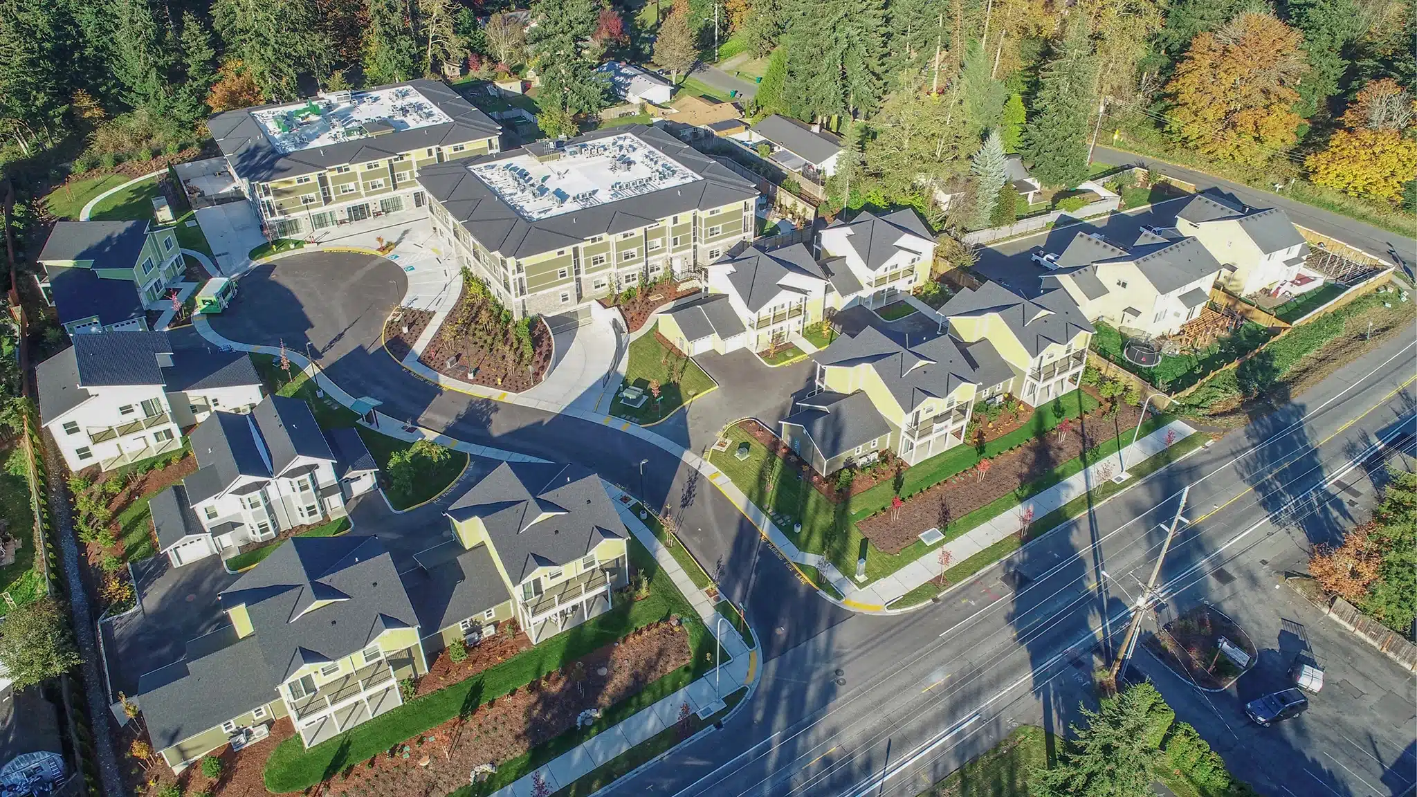 Aerial view of a senior living community with multiple residential buildings surrounded by trees.