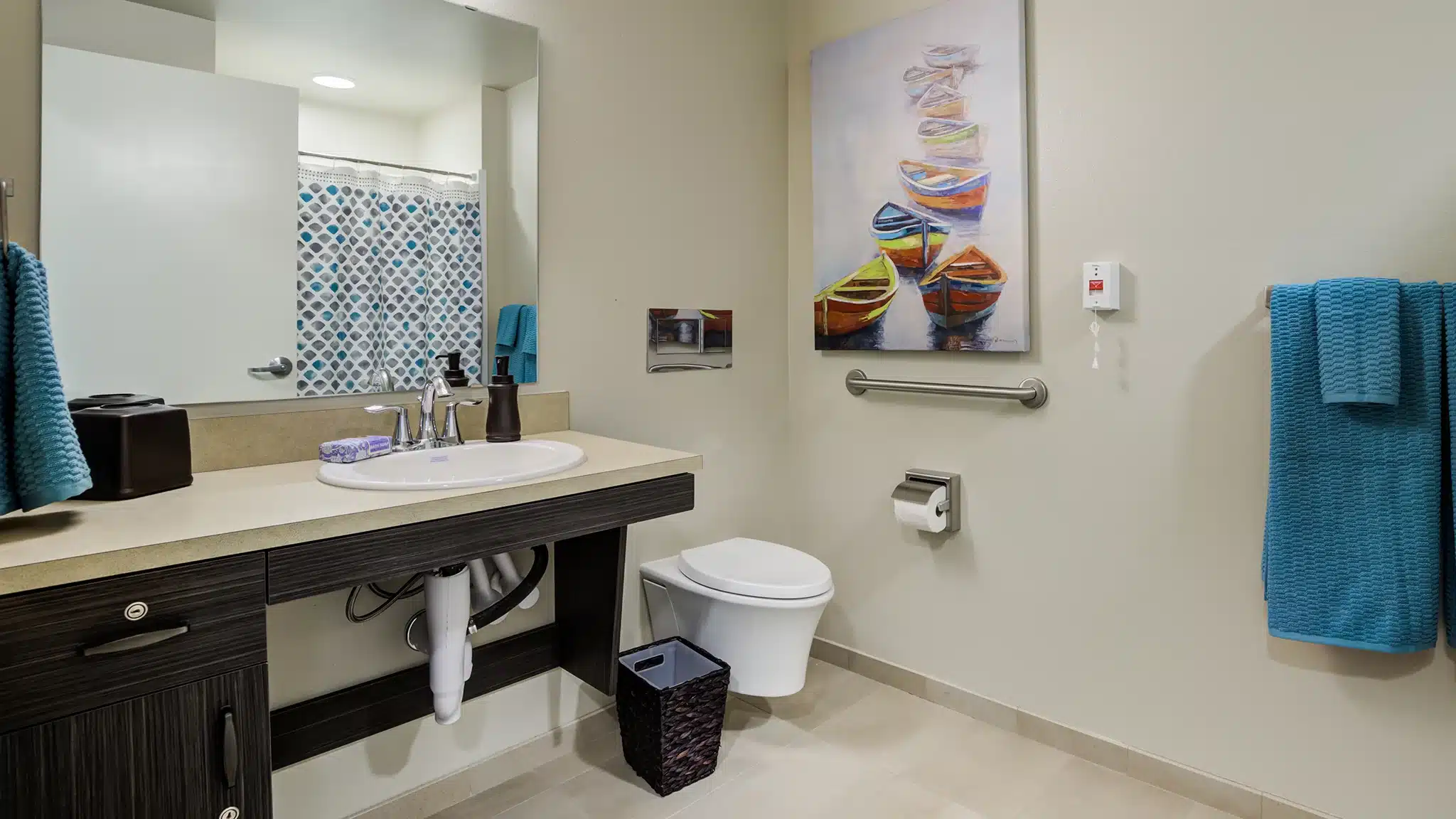 Accessible bathroom with grab bars, sink, and towels in a senior living apartment.
