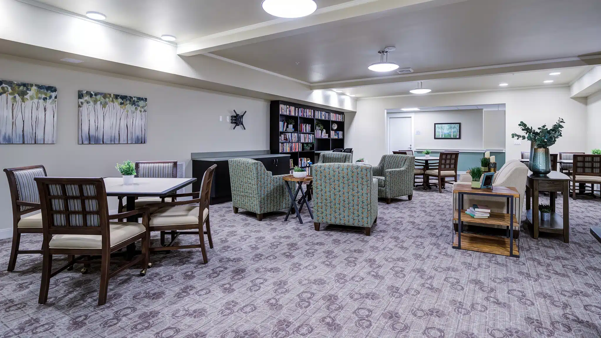 Community lounge with seating areas and tables designed for senior residents