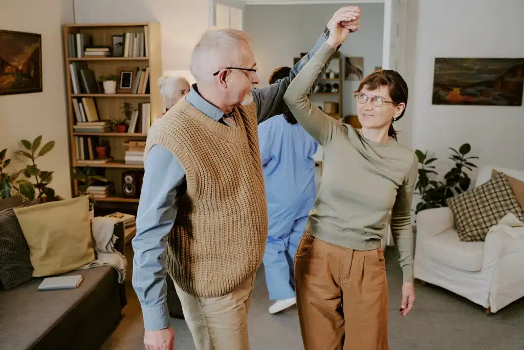 Two older adults smiling and dancing together during an independent living activity.