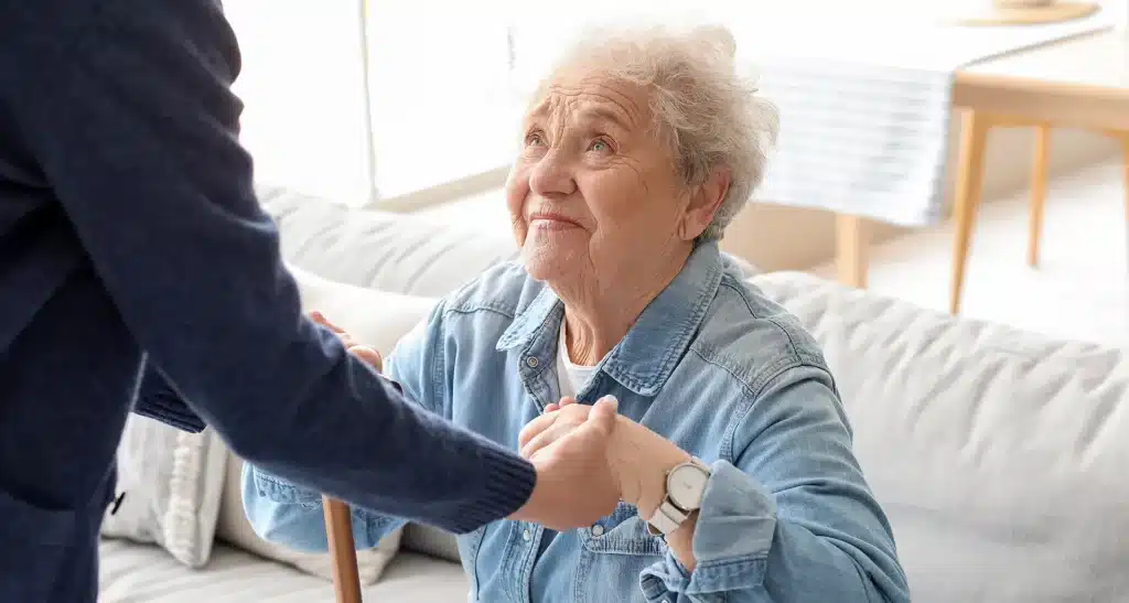 Older adult smiling while holding hands with a caregiver during respite care support.